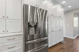 Kitchen featuring white cabinets, stainless steel fridge, and laminate/wood-style floors.