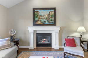 Living room with lofted ceiling, a fireplace, and laminate/wood-style floors.