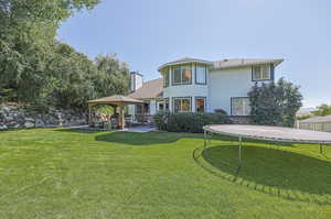 Back of property featuring a trampoline, a gazebo, a yard, and a patio area