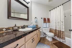 Full bathroom featuring shower / bath combination with curtain, vanity, and toilet