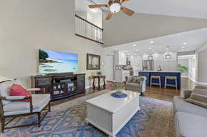 Living room with high vaulted ceiling, ceiling fan, sink, and laminate/wood-style floors.