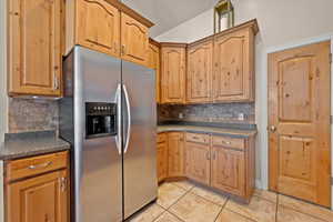 Kitchen featuring stainless steel fridge, decorative backsplash, and light tile patterned flooring