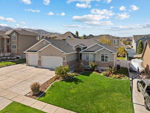 View of front of home featuring cooling unit, a mountain view, a front yard, and a garage