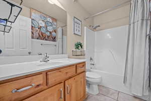 Full bathroom featuring vanity, shower / bath combo with shower curtain, toilet, and tile patterned flooring