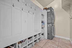 Mudroom with stacked washer / drying machine, light tile patterned flooring, and a textured ceiling