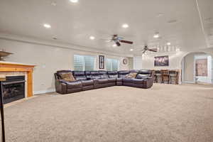 Living room featuring ceiling fan, light carpet, and a fireplace