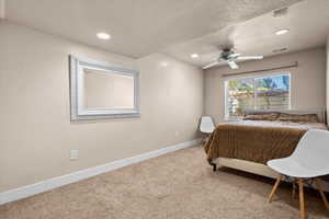 Carpeted bedroom with a textured ceiling and ceiling fan