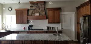 Kitchen with sink, a center island, appliances with stainless steel finishes, and decorative light fixtures