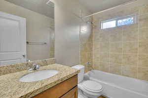 Full bathroom with toilet, tiled shower / bath, and vanity