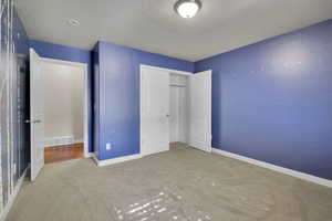 Bedroom with a closet, carpet, and a textured ceiling