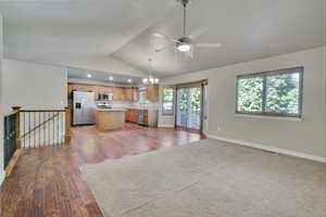 Kitchen featuring dark wood-type flooring, stainless steel appliances, a center island, vaulted ceiling, and decorative light fixtures