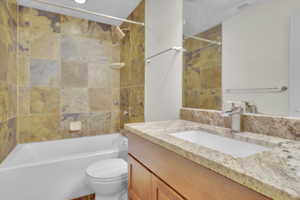 Full bathroom featuring tiled shower / bath, vanity, and toilet