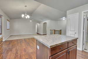 Kitchen featuring lofted ceiling, a kitchen island, hardwood / wood-style floors, decorative light fixtures, and ceiling fan