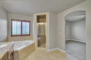 Master Bathroom with vanity, a textured ceiling, separate shower and tub, and tile patterned flooring