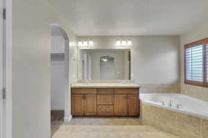 Master Bathroom with vanity, a textured ceiling, tiled bath, and tile patterned flooring