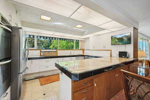 Kitchen with white cabinetry, light tile patterned flooring, plenty of natural light, and stainless steel fridge