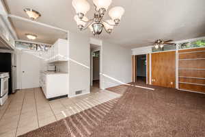 Kitchen with ceiling fan with notable chandelier, white electric range oven, white cabinetry, and a textured ceiling