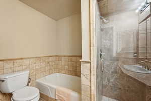 Full bathroom with toilet, tile walls, and separate shower and tub