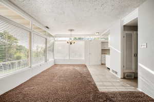 Unfurnished sunroom featuring a notable chandelier