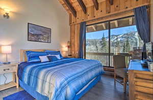 Bedroom with a mountain view, lofted ceiling with beams, and dark hardwood / wood-style flooring