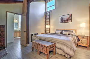 Bedroom featuring hardwood / wood-style flooring, connected bathroom, and high vaulted ceiling