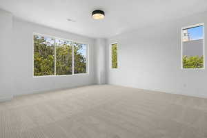 Primary Bedroom with plenty of natural light and light carpet