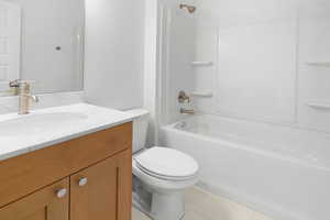 Full bathroom featuring tub / shower combination, vanity, toilet, and tile patterned floors