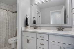 Bathroom featuring vanity, curtained shower, toilet, and tile patterned floors