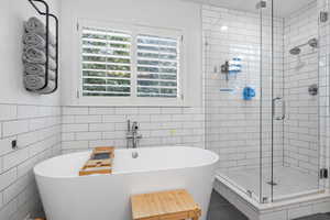 Bathroom featuring tile walls and separate shower and tub