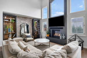 Living room with hardwood / wood-style floors, a towering ceiling, and plenty of natural light