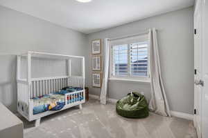 Carpeted bedroom featuring a nursery area