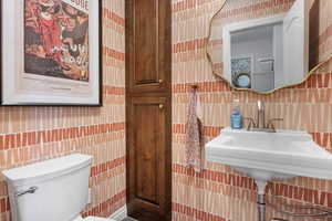 Bathroom with toilet and tile walls