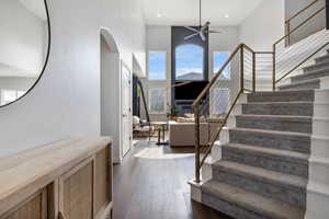 Stairway with wood-type flooring, a towering ceiling, and ceiling fan