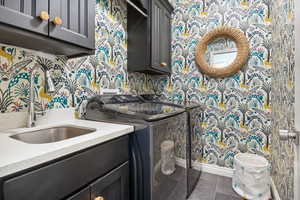 Laundry room featuring cabinets, dark tile patterned floors, sink, and washing machine and dryer