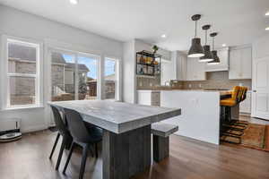 Kitchen featuring tasteful backsplash, a center island, white cabinetry, pendant lighting, and dark hardwood / wood-style floors