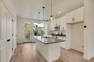 Kitchen with dark countertops, a sink, light wood-style flooring, appliances with stainless steel finishes, and recessed lighting