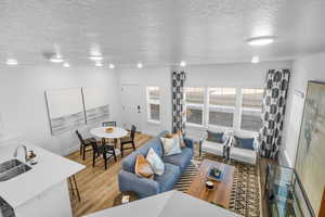 Living room with light hardwood / wood-style flooring, a textured ceiling, and sink