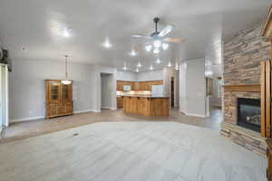 Unfurnished living room with a stone fireplace, a textured ceiling, light tile patterned flooring, and ceiling fan