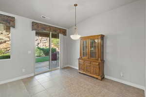 Unfurnished dining area with light tile patterned floors, vaulted ceiling, and a wealth of natural light