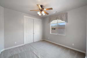 Unfurnished bedroom featuring a closet, carpet floors, and ceiling fan