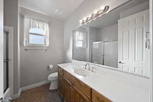 Bathroom featuring toilet, a shower with shower door, vanity, and tile patterned flooring