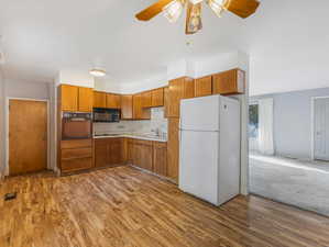 Kitchen with light hardwood / wood-style floors, black appliances, sink, and ceiling fan