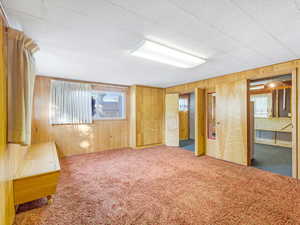 Carpeted spare room with wood walls