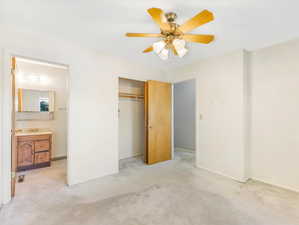 Unfurnished bedroom featuring light colored carpet, a closet, and ceiling fan