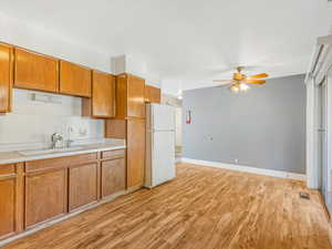 Kitchen featuring light hardwood / wood-style floors, sink, white refrigerator, and ceiling fan