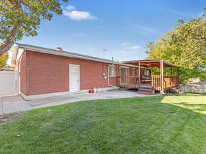 Rear view of property with a wooden deck, a patio area, and a lawn