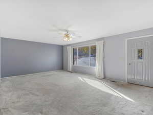 Empty room featuring light carpet and ceiling fan