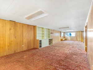 Carpeted spare room with wood walls