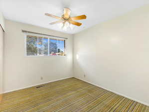 Carpeted empty room with ceiling fan