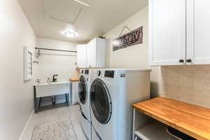 Washroom featuring cabinets, sink, separate washer and dryer, and light tile patterned floors